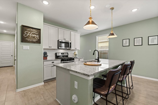 kitchen featuring a breakfast bar area, white cabinetry, stainless steel appliances, and a kitchen island with sink