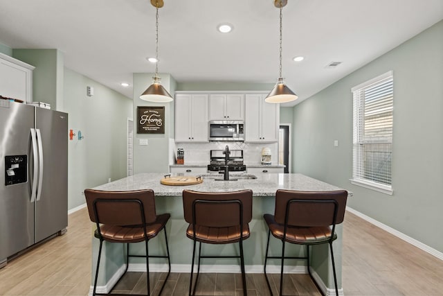 kitchen featuring visible vents, a sink, stainless steel appliances, white cabinets, and tasteful backsplash