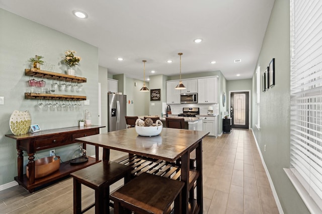 dining room with wood finish floors, recessed lighting, a dry bar, and baseboards