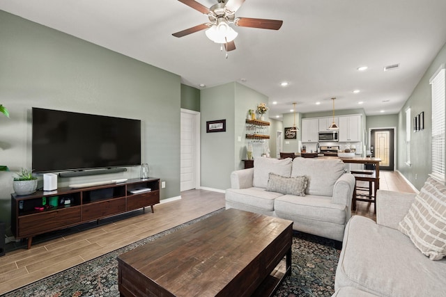 living room featuring visible vents, recessed lighting, baseboards, ceiling fan, and wood tiled floor