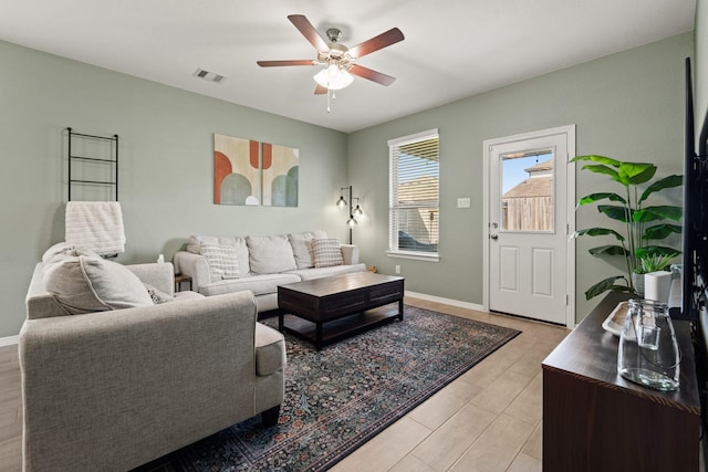 living area with a ceiling fan, visible vents, and baseboards