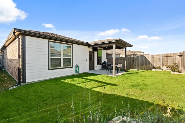 back of property with a yard, brick siding, a fenced backyard, and a patio area