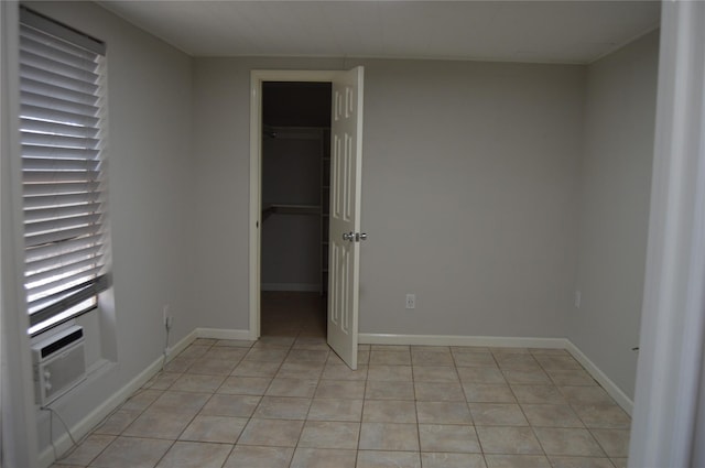 unfurnished bedroom with a spacious closet, a closet, baseboards, and light tile patterned flooring