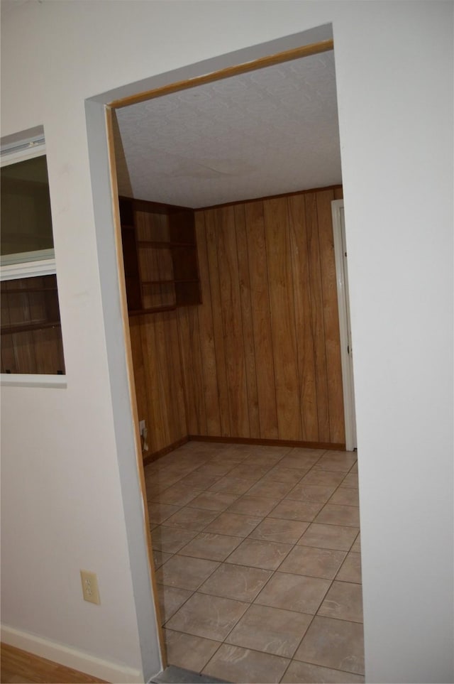 hall with wooden walls, baseboards, and a textured ceiling