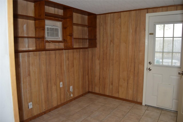 spare room featuring an AC wall unit, baseboards, and wood walls