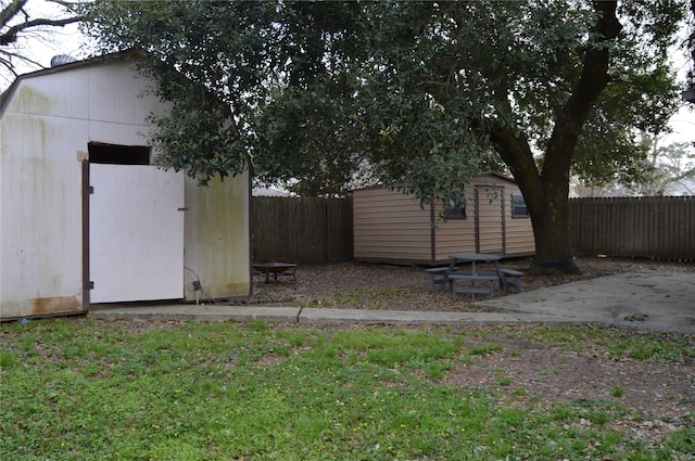 view of yard featuring a storage shed, a fenced backyard, and an outdoor structure