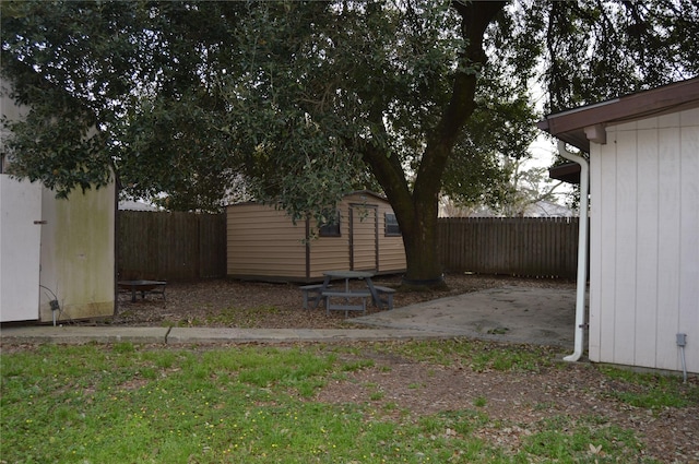 view of yard with an outdoor structure, a fenced backyard, a shed, and a patio