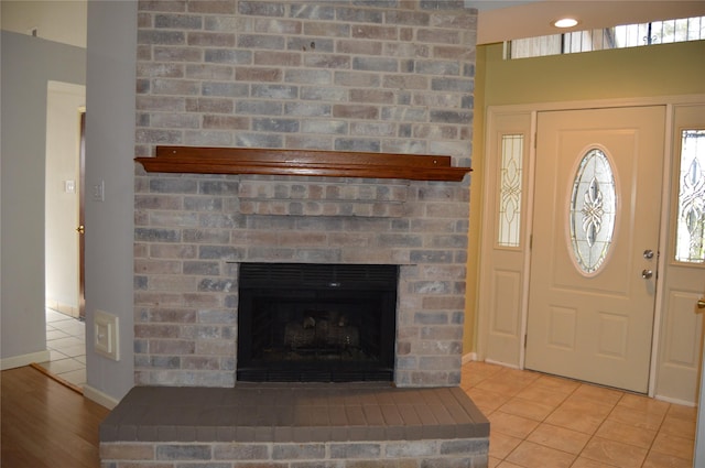 entrance foyer with a brick fireplace, light tile patterned floors, and baseboards