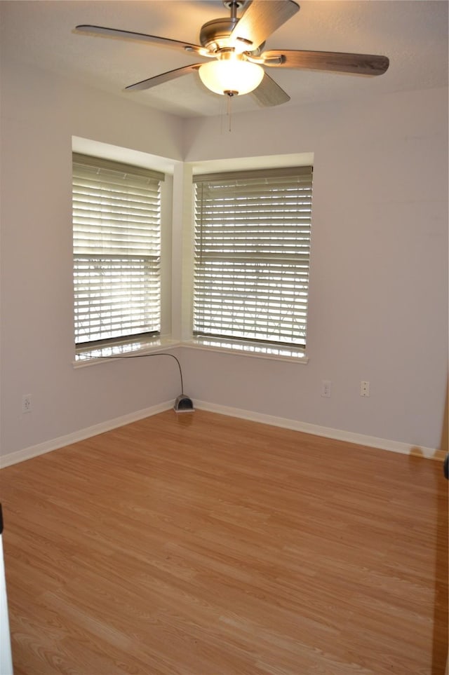 empty room featuring baseboards, wood finished floors, and a ceiling fan