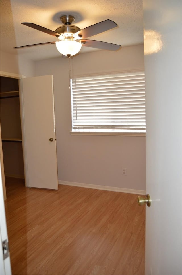 unfurnished bedroom with baseboards, light wood-type flooring, a closet, and a textured ceiling