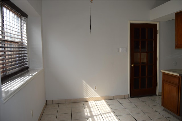 unfurnished dining area with light tile patterned floors and baseboards