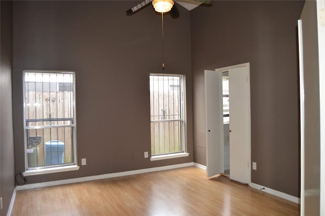 unfurnished room featuring ceiling fan, baseboards, a healthy amount of sunlight, and wood finished floors