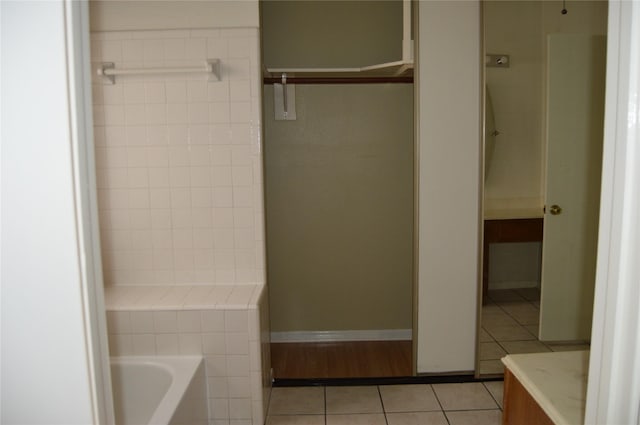 bathroom with baseboards, a bathing tub, and tile patterned flooring