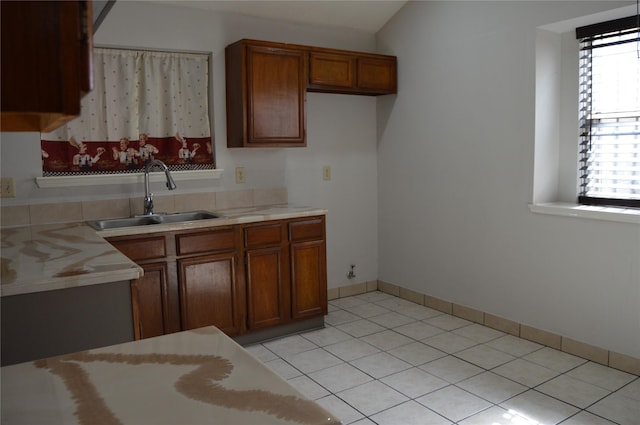 kitchen featuring a sink, brown cabinets, light tile patterned floors, and light countertops