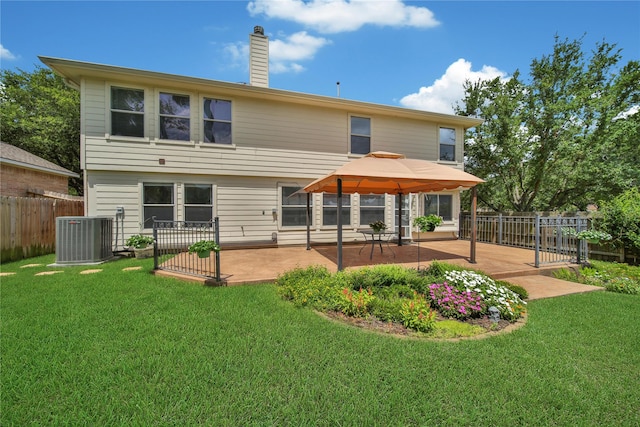 rear view of property with cooling unit, fence, a chimney, a patio area, and a lawn