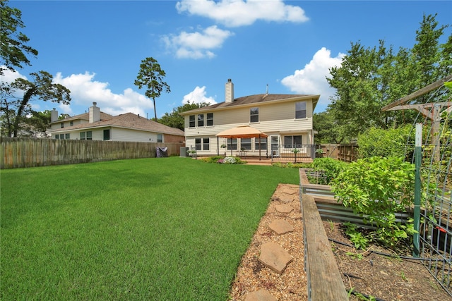 back of property with a garden, a yard, a fenced backyard, a chimney, and a gazebo