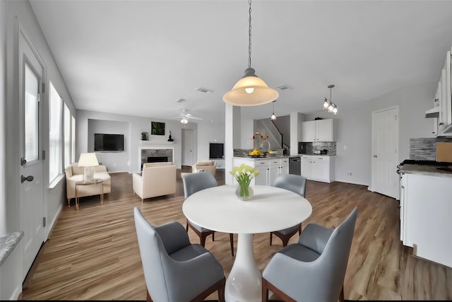 dining area featuring radiator heating unit, wood finished floors, visible vents, and a high end fireplace