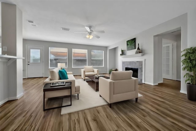 living room featuring visible vents, wood finished floors, a ceiling fan, and a premium fireplace