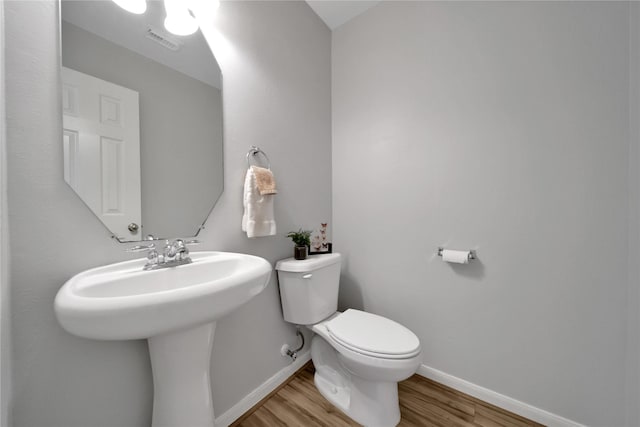 bathroom with visible vents, toilet, baseboards, and wood finished floors