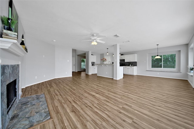 unfurnished living room with light wood finished floors, a healthy amount of sunlight, visible vents, and a high end fireplace