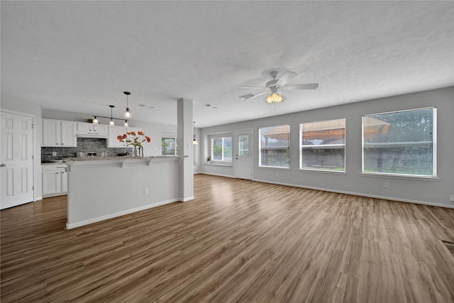 kitchen featuring tasteful backsplash, dark wood finished floors, open floor plan, a breakfast bar area, and white cabinets