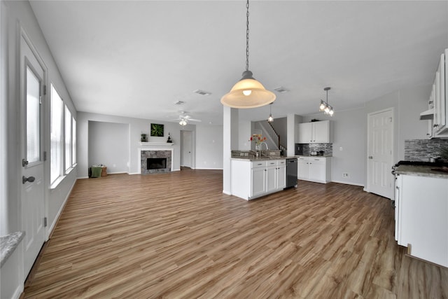 kitchen featuring light wood finished floors, open floor plan, dishwasher, and decorative backsplash