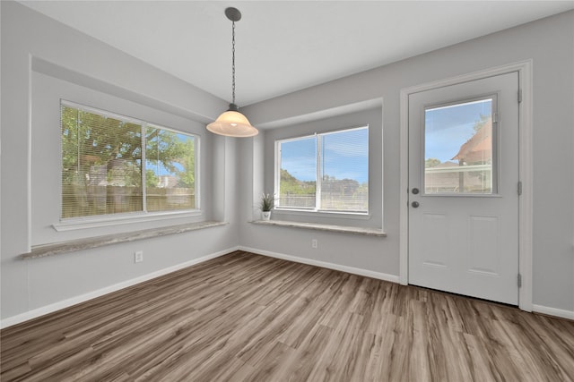 unfurnished dining area with baseboards and wood finished floors