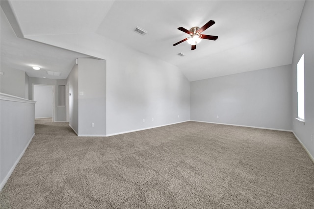 carpeted spare room featuring visible vents, baseboards, and lofted ceiling