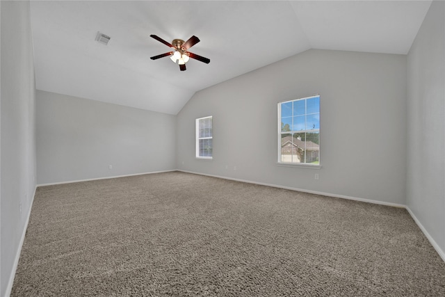 carpeted spare room with vaulted ceiling, baseboards, visible vents, and ceiling fan