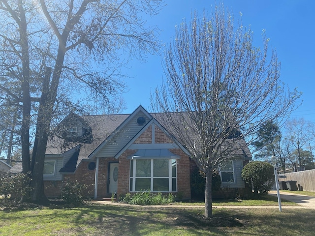 view of front of property with brick siding, a front yard, and fence