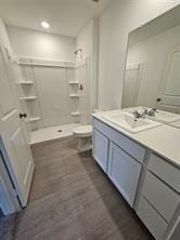 bathroom with vanity, toilet, wood finished floors, and walk in shower