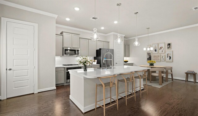 kitchen with appliances with stainless steel finishes, decorative backsplash, a kitchen breakfast bar, a kitchen island with sink, and recessed lighting