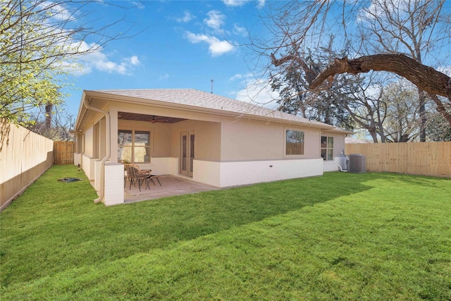 back of property featuring ceiling fan, central air condition unit, stucco siding, a fenced backyard, and a yard