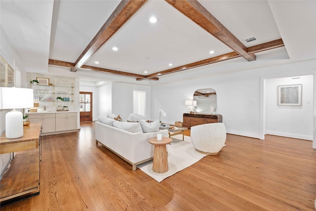 living area featuring beam ceiling, visible vents, light wood-style flooring, and baseboards