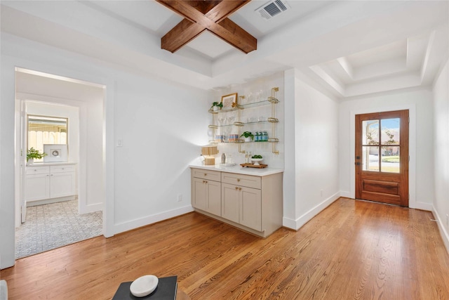 bar with visible vents, baseboards, beam ceiling, light wood-style floors, and coffered ceiling