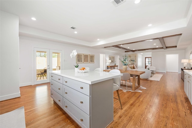 kitchen featuring visible vents, gray cabinetry, a breakfast bar area, and light wood finished floors