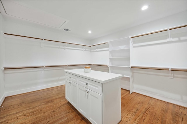 spacious closet with attic access, visible vents, and light wood finished floors