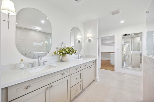 bathroom with double vanity, visible vents, a shower with shower door, and a sink