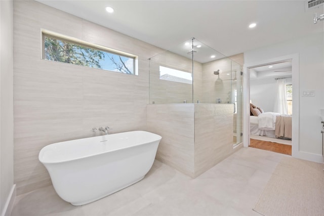 full bath featuring visible vents, a freestanding tub, a stall shower, tile walls, and connected bathroom