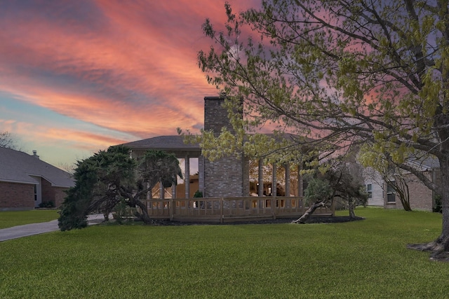 view of front of property featuring a lawn, a chimney, and a wooden deck