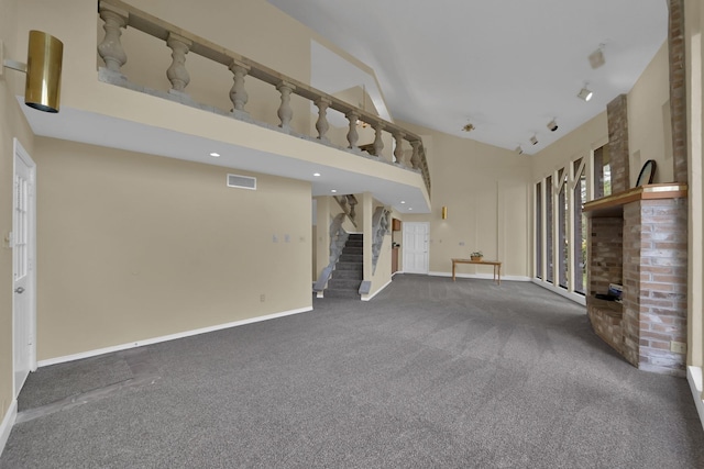 unfurnished living room with baseboards, visible vents, a fireplace, stairs, and carpet flooring