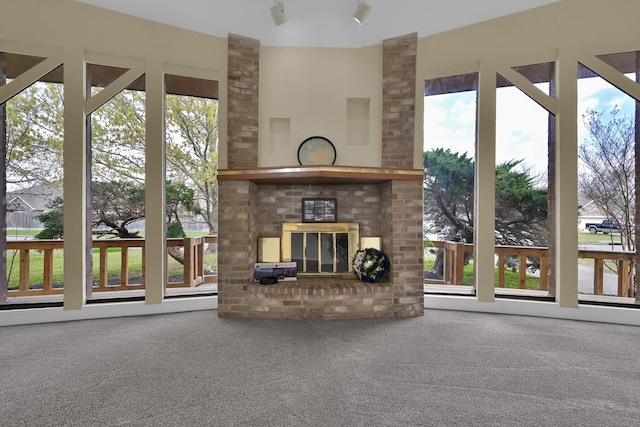 unfurnished living room featuring a brick fireplace, a baseboard heating unit, and carpet