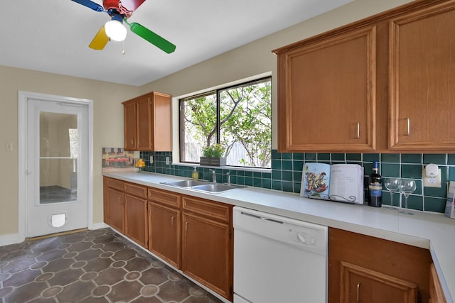 kitchen featuring brown cabinets, a sink, tasteful backsplash, light countertops, and dishwasher