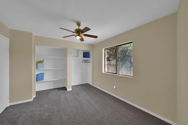 unfurnished bedroom with baseboards, dark carpet, and ceiling fan