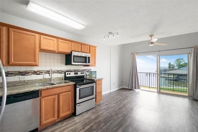 kitchen featuring a sink, backsplash, a textured ceiling, wood finished floors, and stainless steel appliances