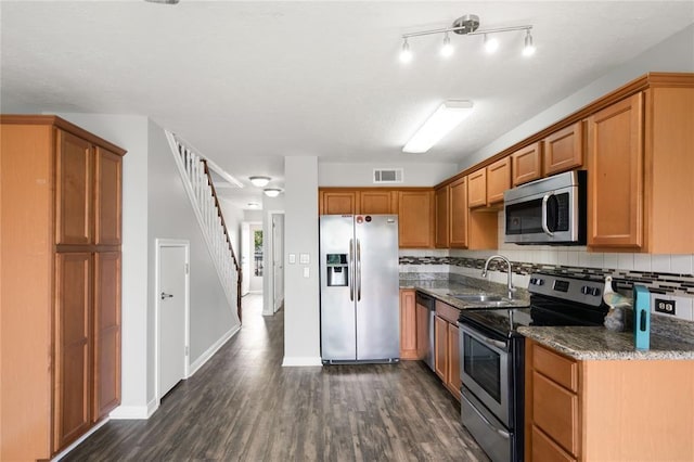 kitchen with visible vents, dark wood-style flooring, a sink, appliances with stainless steel finishes, and brown cabinets