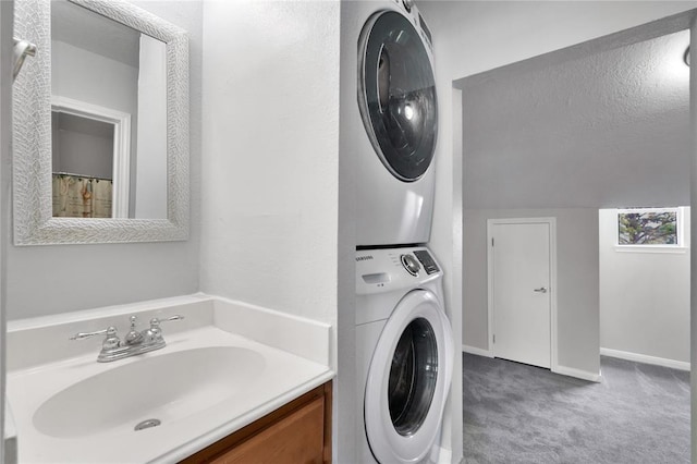 washroom with baseboards, carpet floors, stacked washer and dryer, laundry area, and a sink