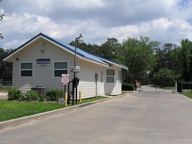 view of side of home featuring a gate and central AC