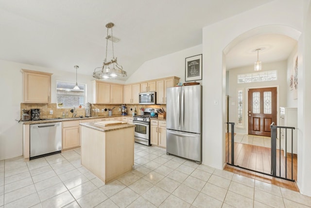 kitchen with stainless steel appliances, arched walkways, plenty of natural light, and light brown cabinetry