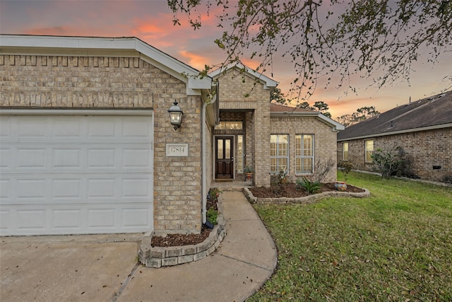 view of front facade featuring brick siding, a lawn, driveway, and a garage